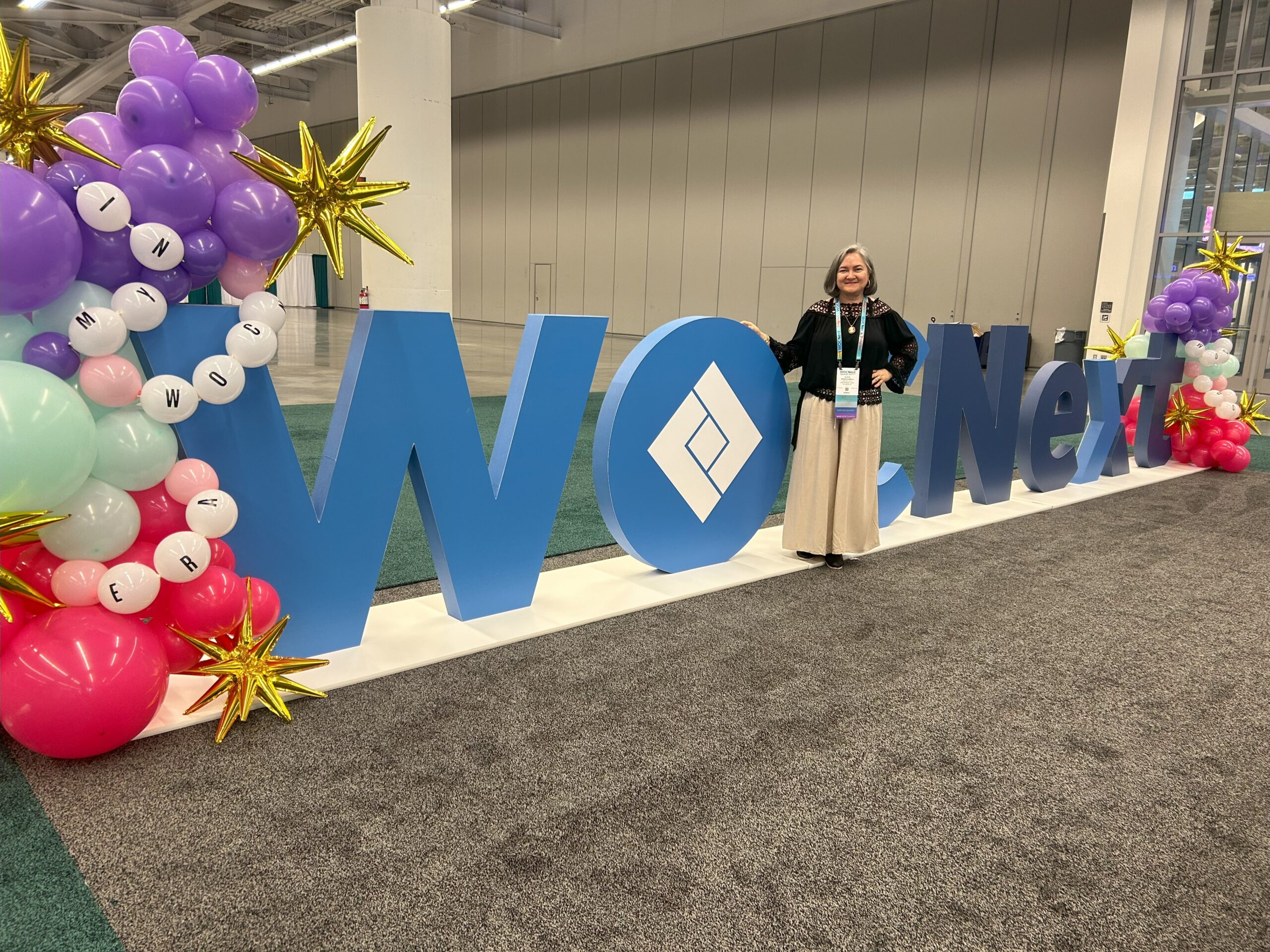 Photo in front of sign at WOCNext. 